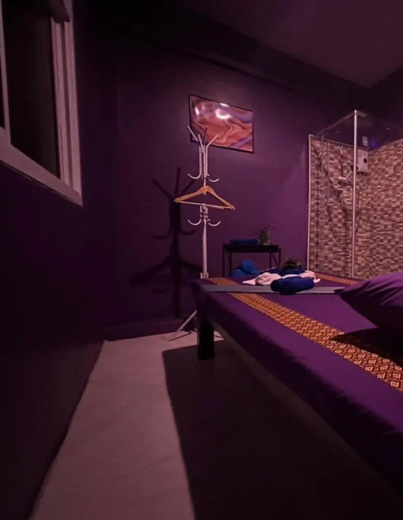 Treatment room with massage bed, coat stand and glass shower